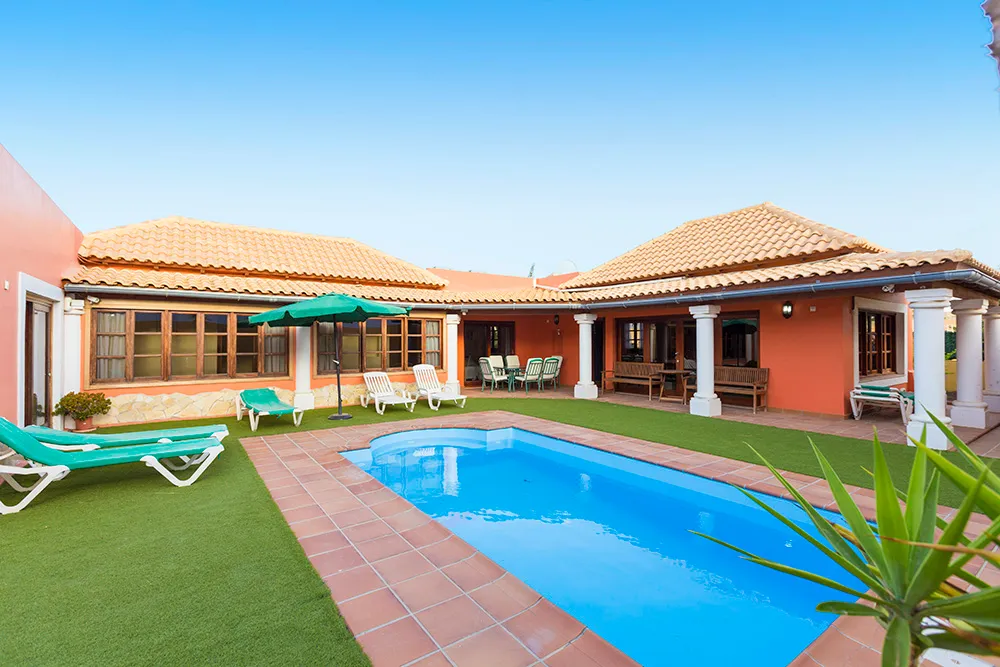 Villa de una planta con piscina, césped y tumbonas en Fuerteventura.